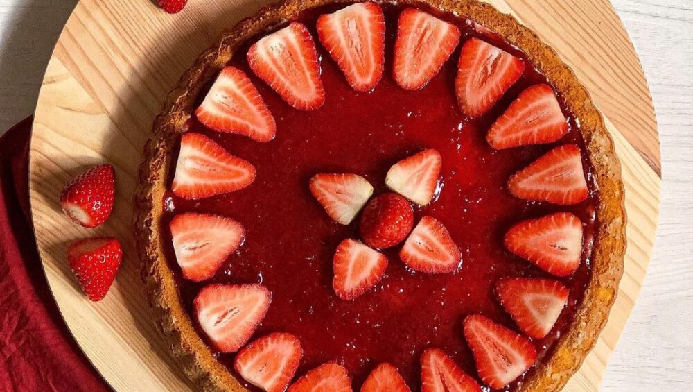 crostata alla marmellata di fragole e decorazione dei fragole su tagliere di legno