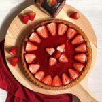crostata alla marmellata di fragole e decorazione dei fragole su tagliere di legno
