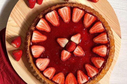 crostata alla marmellata di fragole e decorazione dei fragole su tagliere di legno