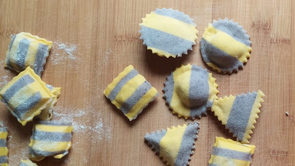 ravioli bicolore al mirtillo sparsi su spianatoia